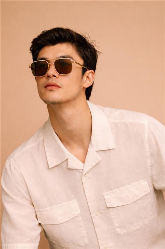 Elegant woman wearing oversized tortoiseshell sunglasses with gold accents in natural sunlight