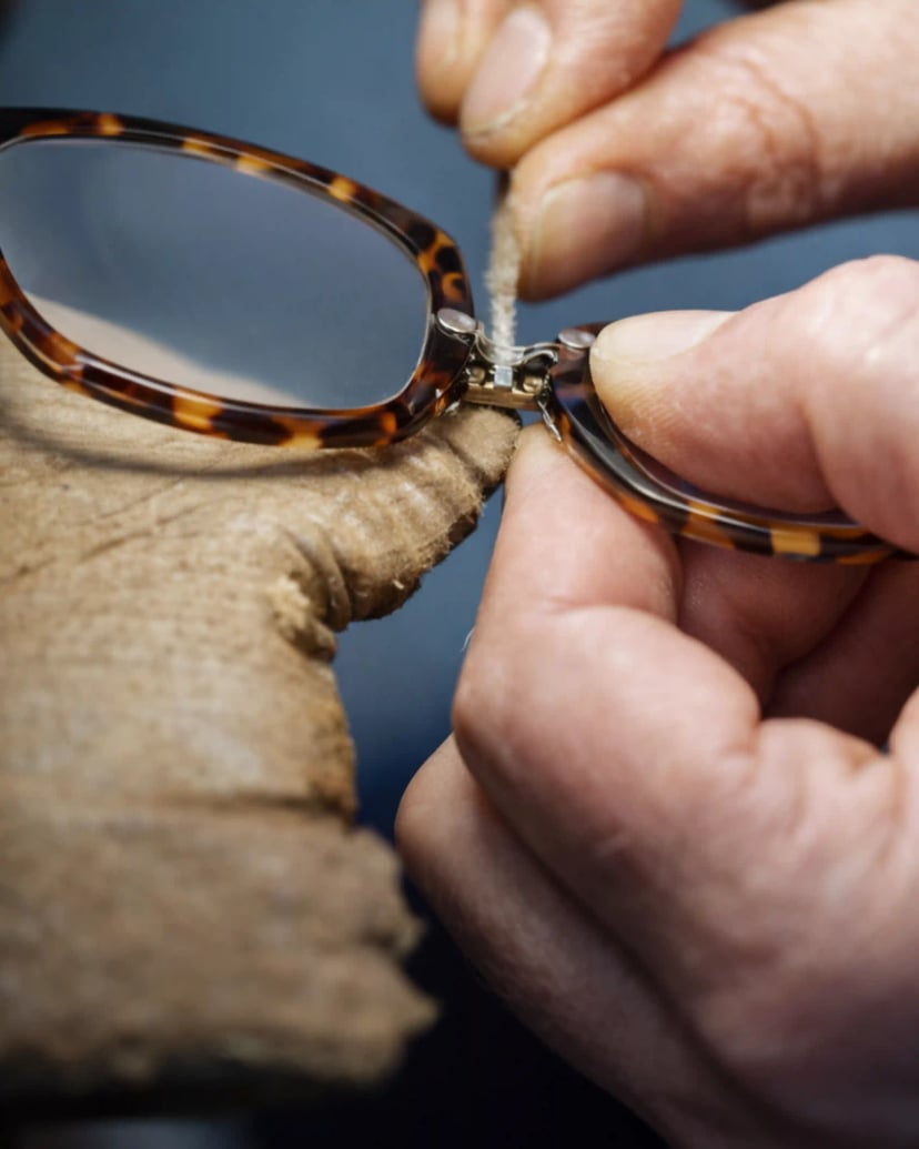 Master craftsman carefully adjusting temple hinge on luxury eyewear frame in traditional workshop